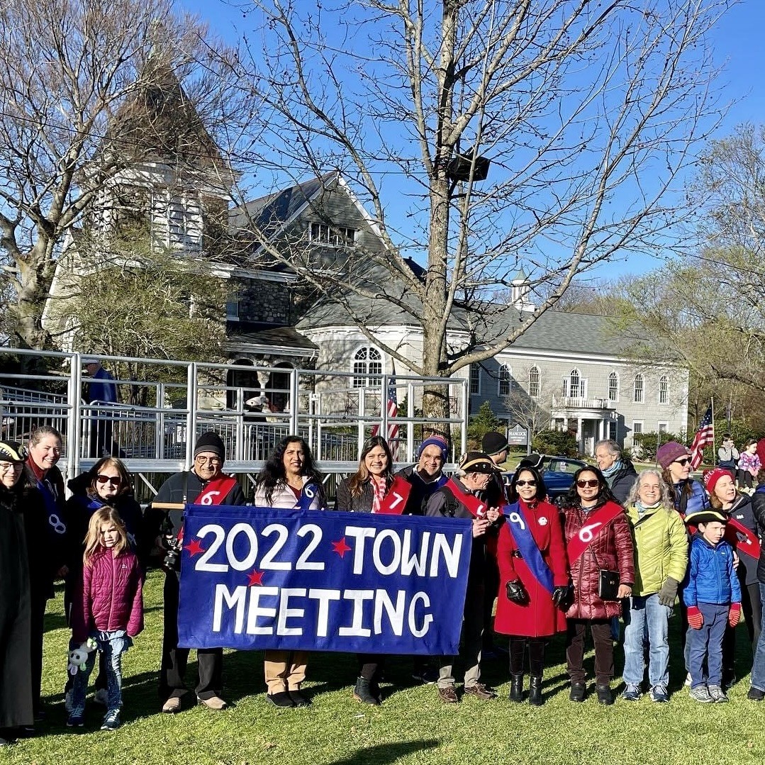 photo of vineeta with a group of about a dozen town meeting members outside holding a banner that says 2022 town meeting